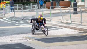 A dedicated athlete competes in a marathon using a racing wheelchair on city streets.